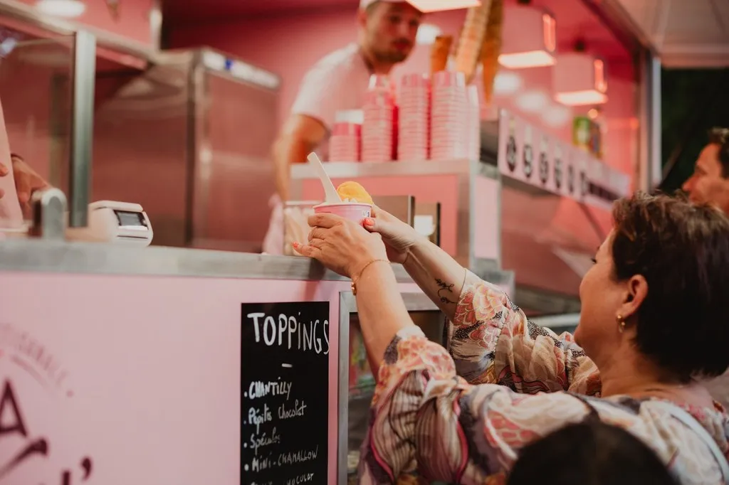 Service d’une glace artisanale au comptoir d’un food truck rose