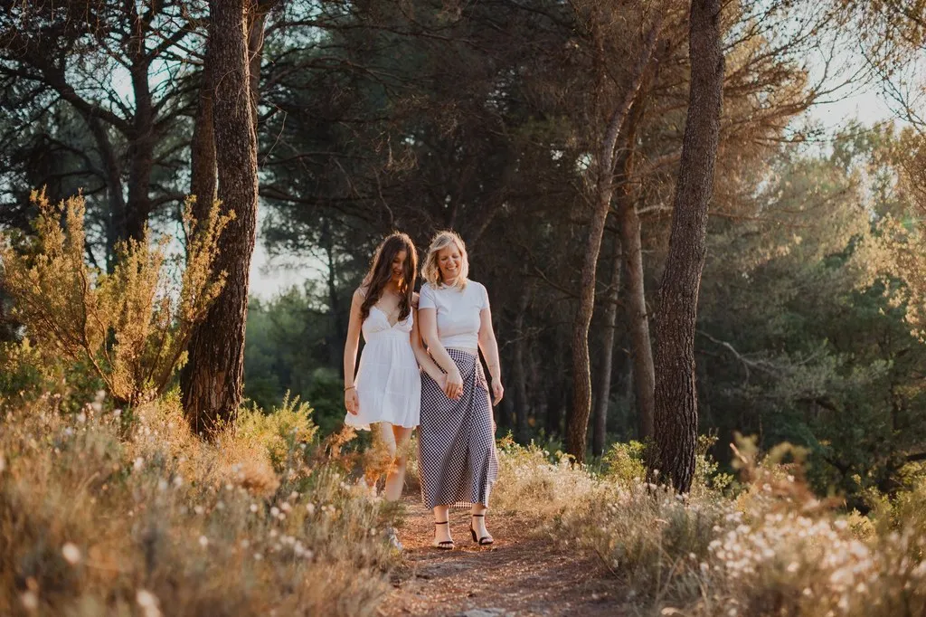 Mère et fille marchant enlacées dans une pinède dorée, séance mère-fille en Pays d’Aix