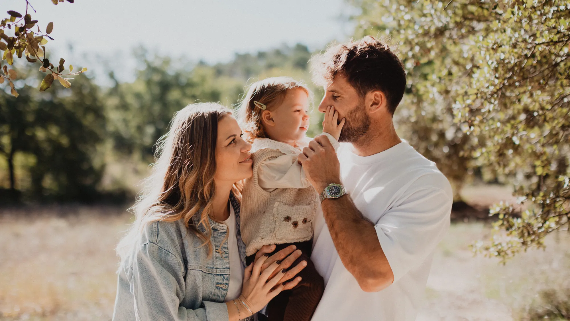 Jeunes parents et leur petite fille complices sous les oliviers, reportage famille en Luberon