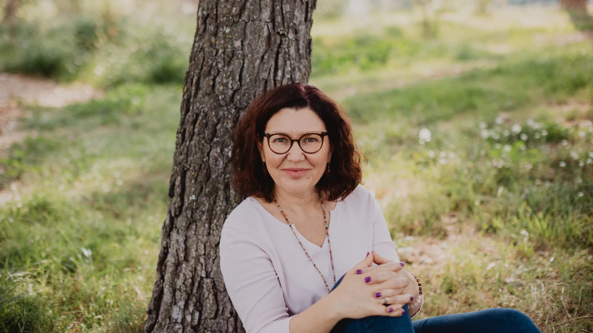 Portrait professionnel d’une entrepreneuse souriante assise au pied d’un arbre