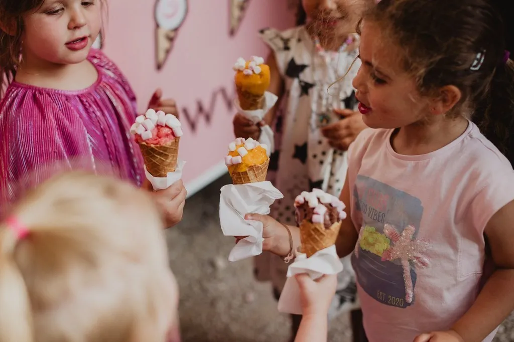 Enfants dégustant leurs cornets devant le camion du glacier