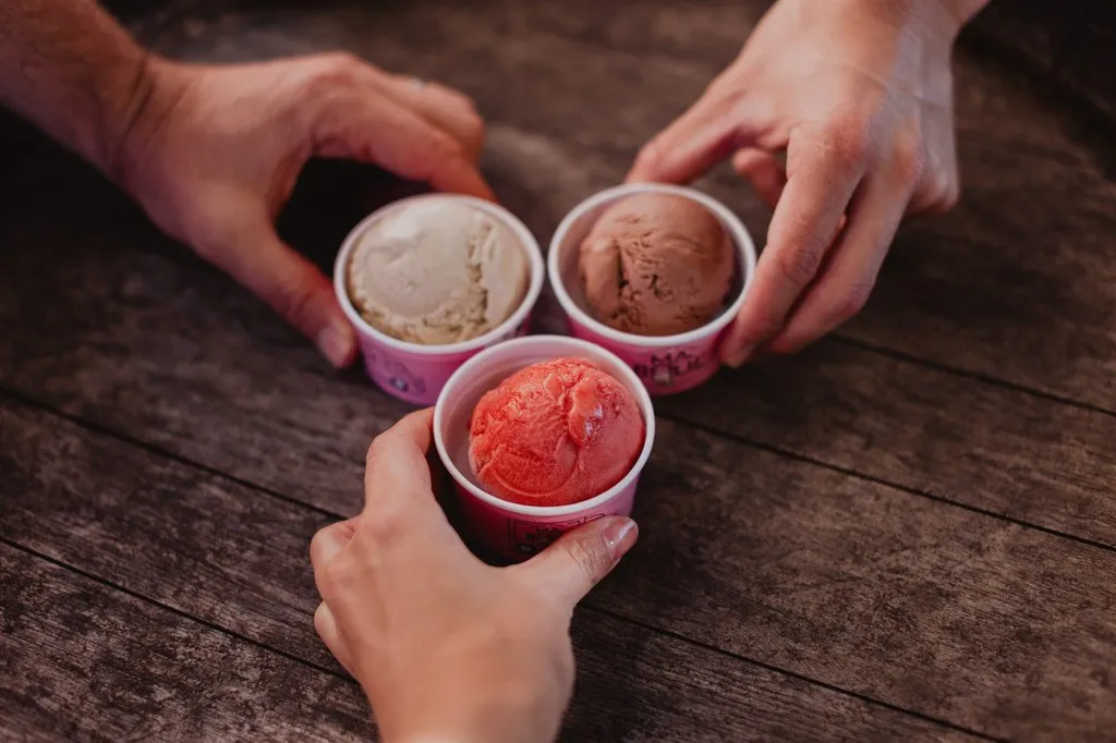 Trois pots de glace artisanale réunis au-dessus d’une table en bois