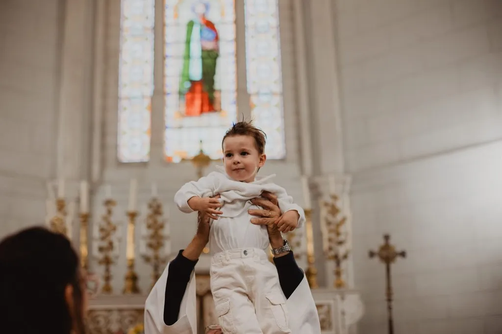 Bébé porté à bout de bras devant l’autel