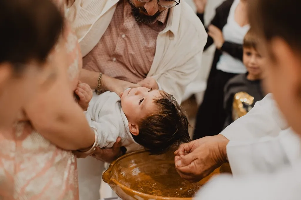 Le prêtre versant l’eau sur le front du bébé