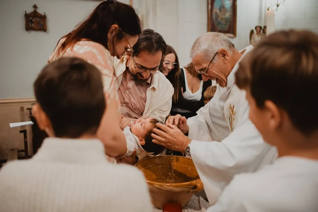 Famille penchée au-dessus des fonts baptismaux