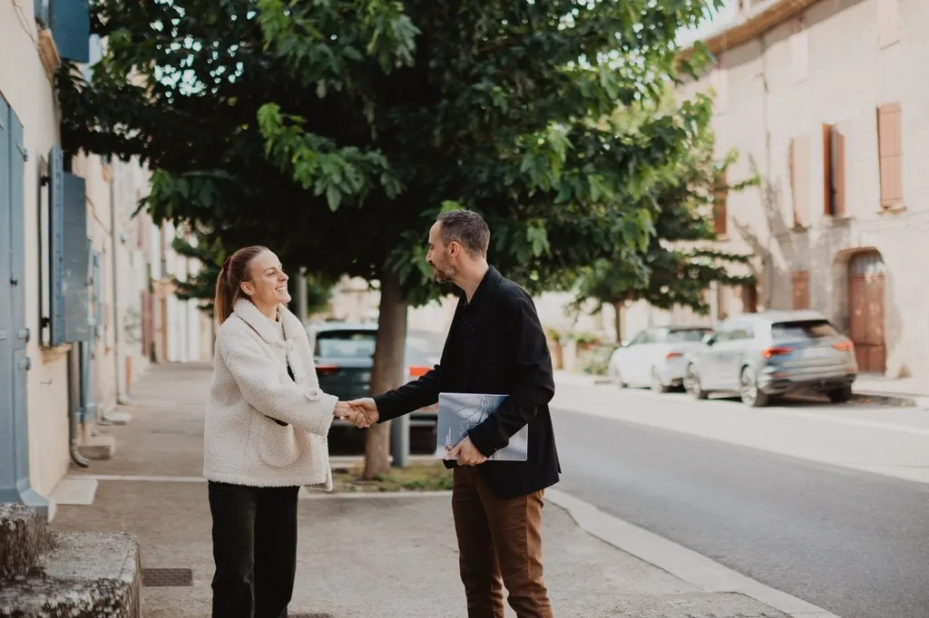 Poignée de main entre un conseiller et sa cliente dans une rue de village