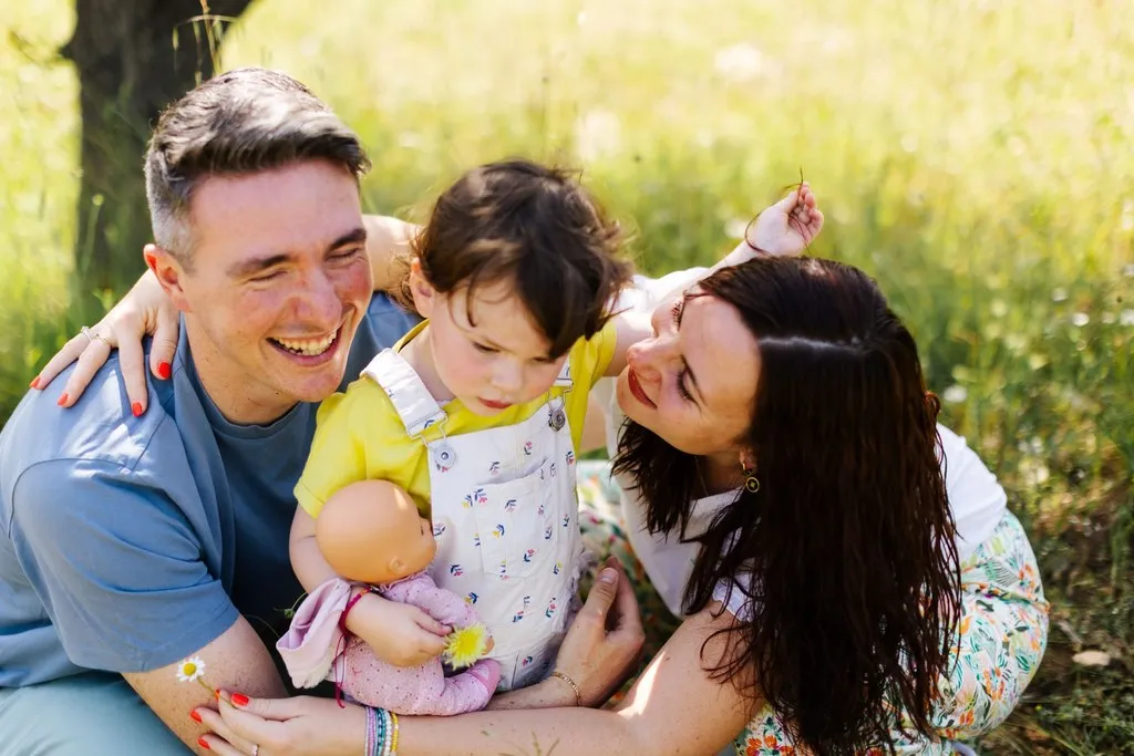 Parents riant avec leur bébé dans l’herbe, séance famille