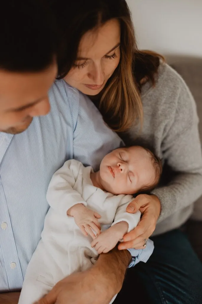 Parents tenant leur nouveau-né endormi, séance naissance à domicile