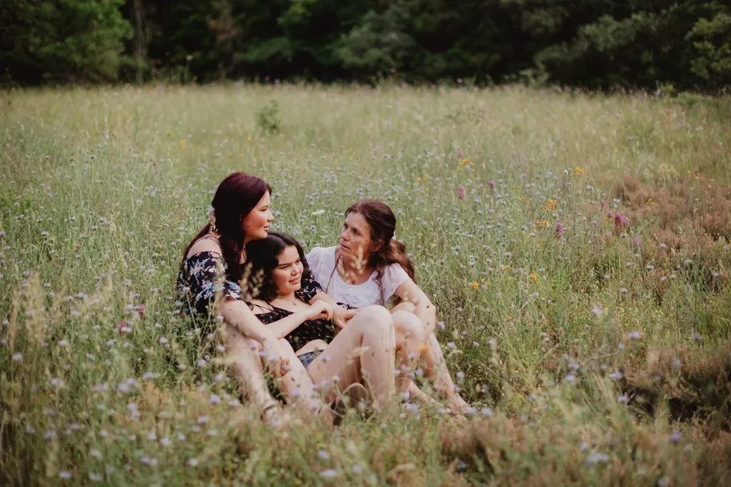 Mère et ses filles assises dans une prairie en fleurs