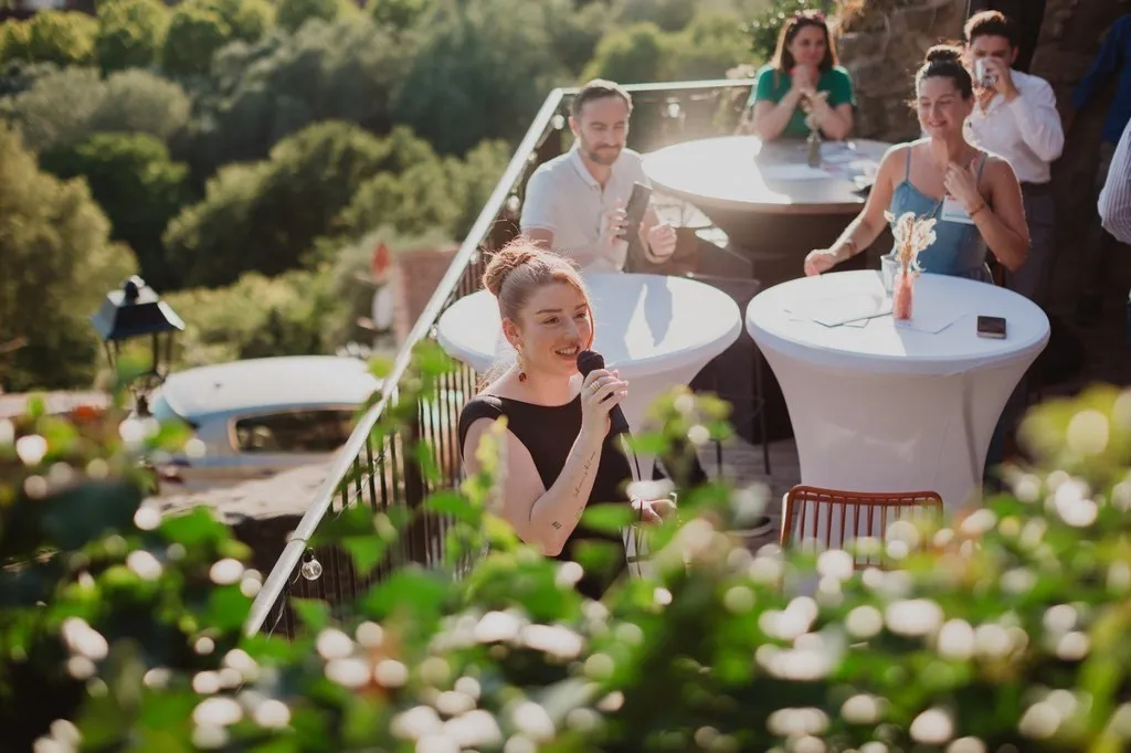 Invités autour d’une table haute sur une terrasse fleurie