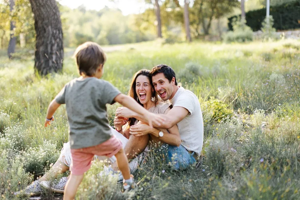 Parents jouant avec leur fils dans l’herbe