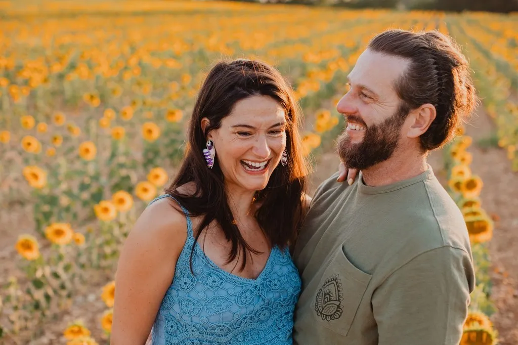 Futurs parents riant dans un champ de tournesols