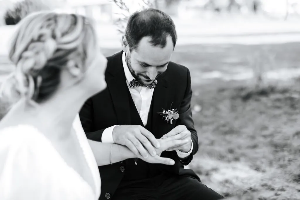 Le marié passant l’alliance au doigt de la mariée, photo en noir et blanc