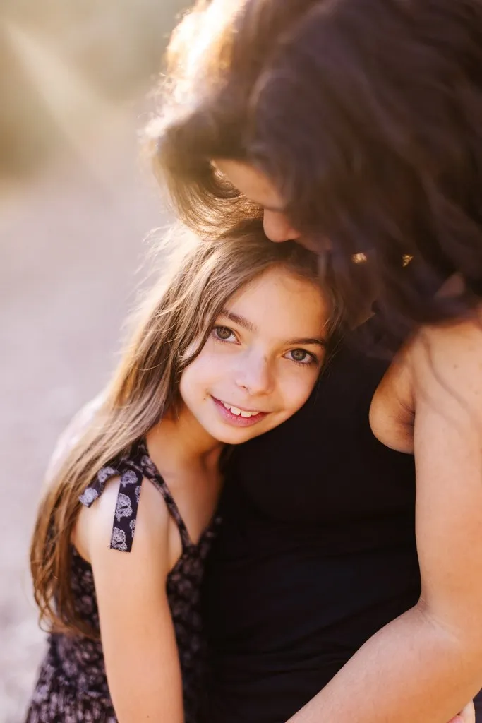 Petite fille blottie contre sa maman en lumière dorée