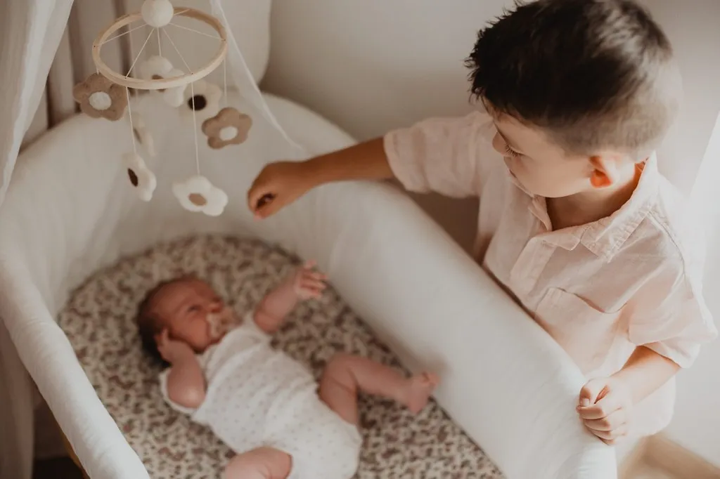 Grand frère veillant sur le bébé dans son couffin