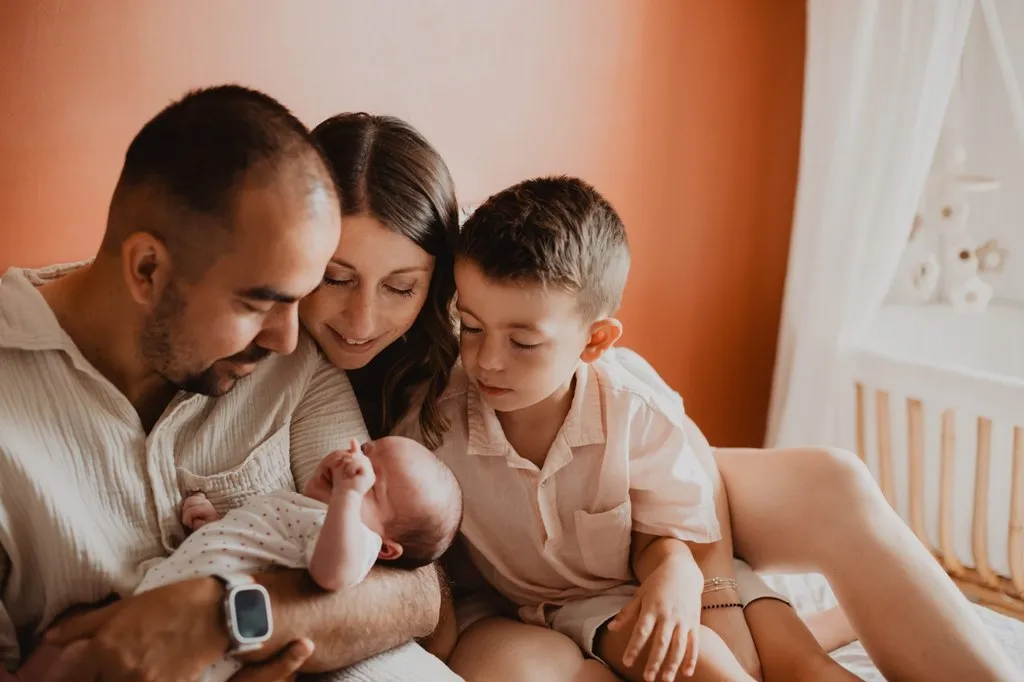 Famille réunie autour du nouveau-né dans la chambre