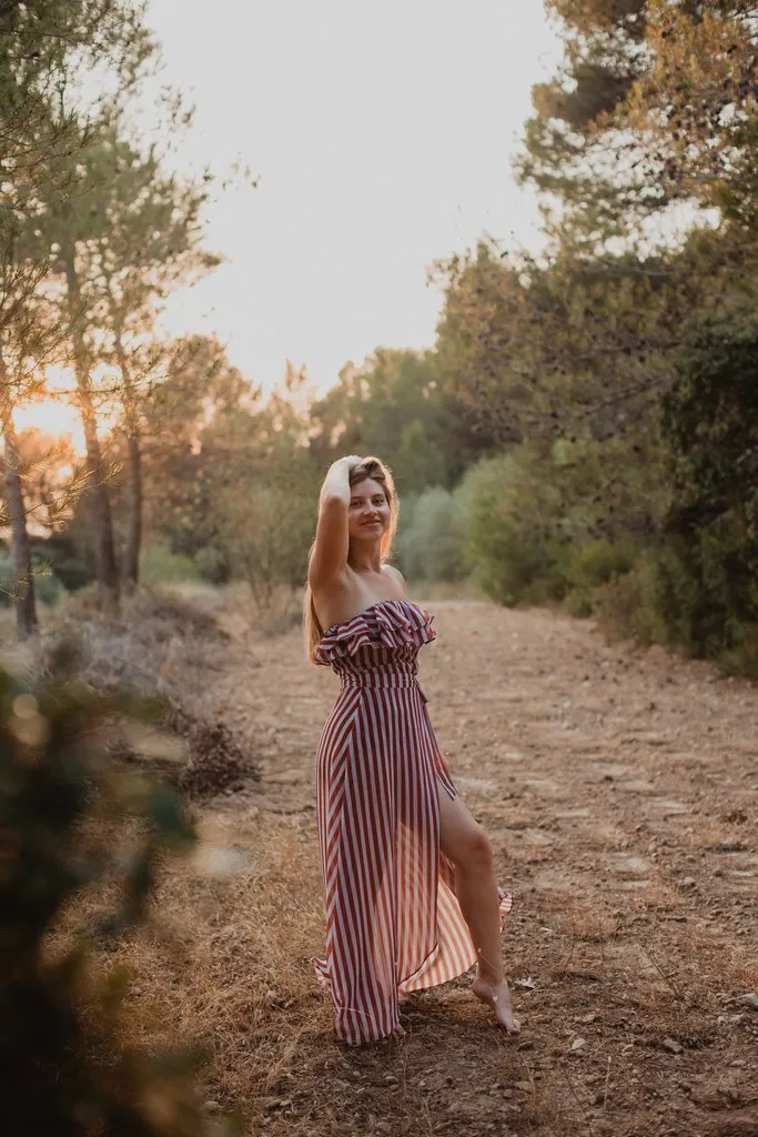Jeune femme en robe longue marchant sur un chemin de pinède