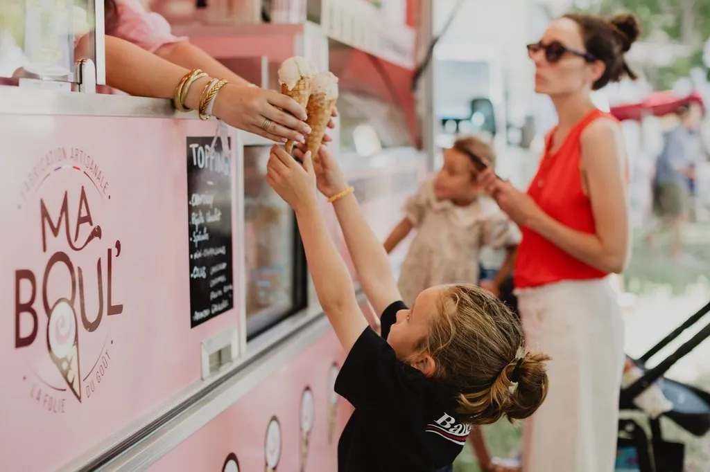 Enfant recevant une glace au comptoir d’un food truck rose